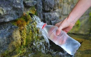 source of spring water bottle filling holding hand in Pyrenees mountain